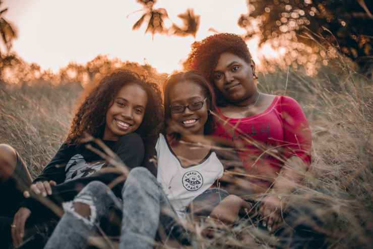 three women sitting on grass